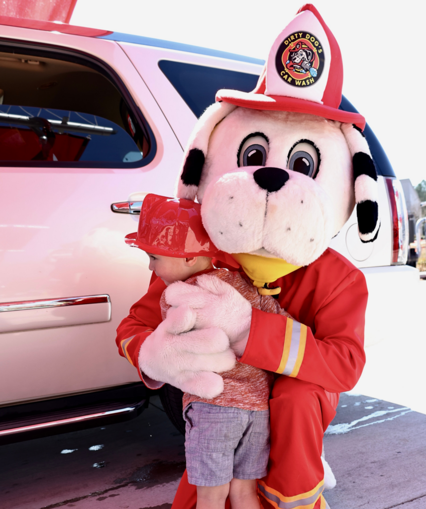 Dirty Dog's mascot, Rescue, hugging child at car wash.